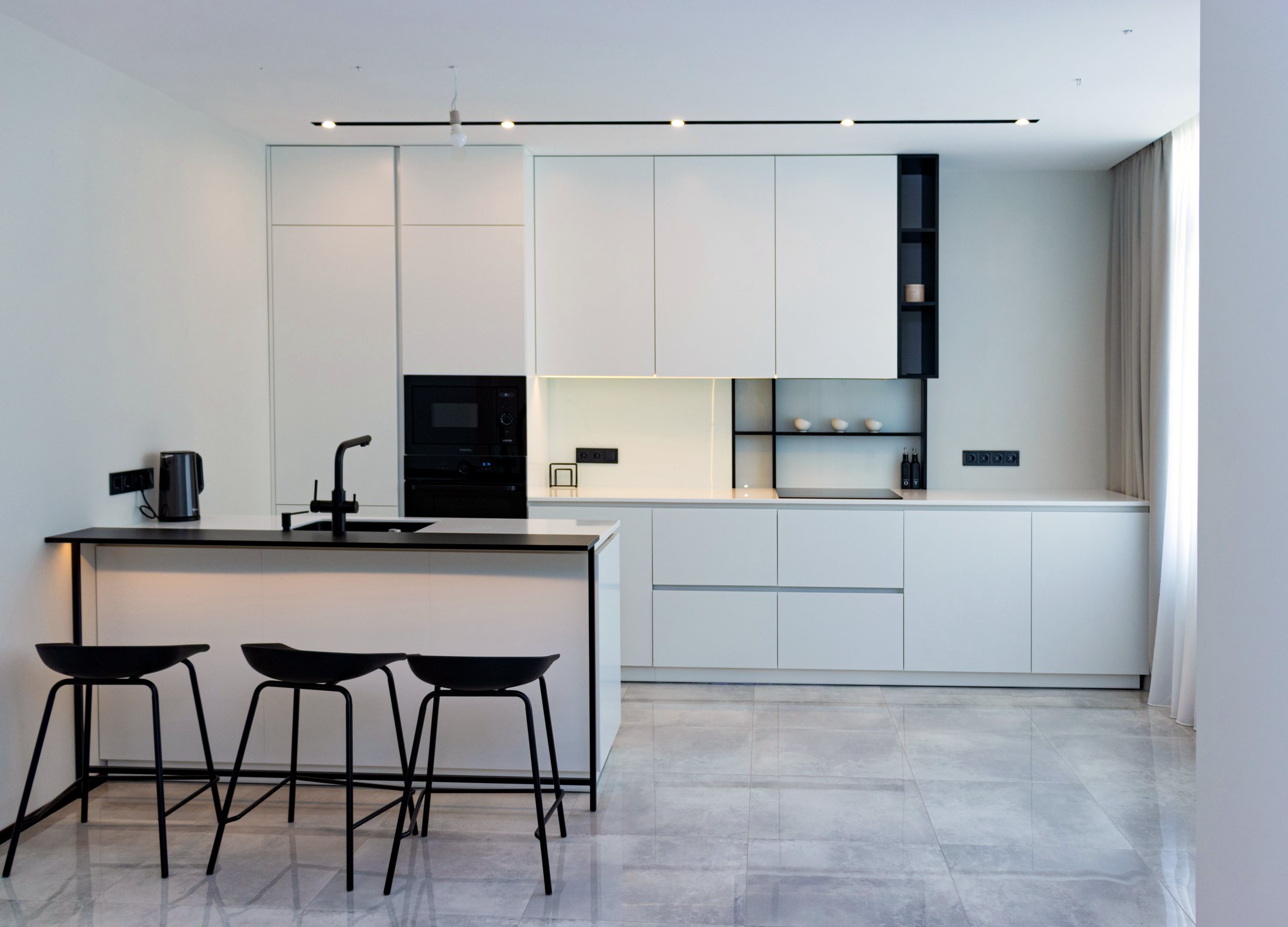 Weiße Küche nach Maß mit Insel und Barhockern in einer Neubauwohnung
